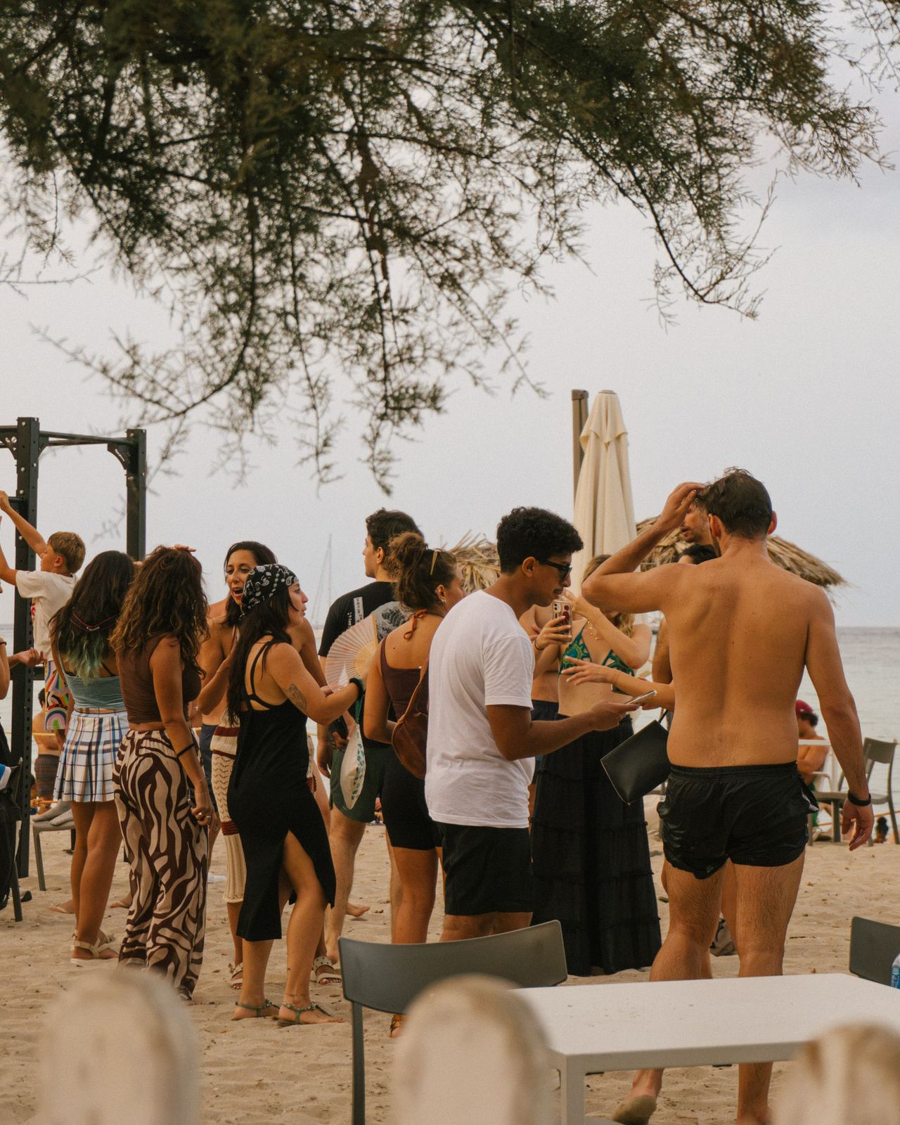 Gruppo di ragazzi attorno a un tavolo durante una festa all'aperto, sotto gli alberi