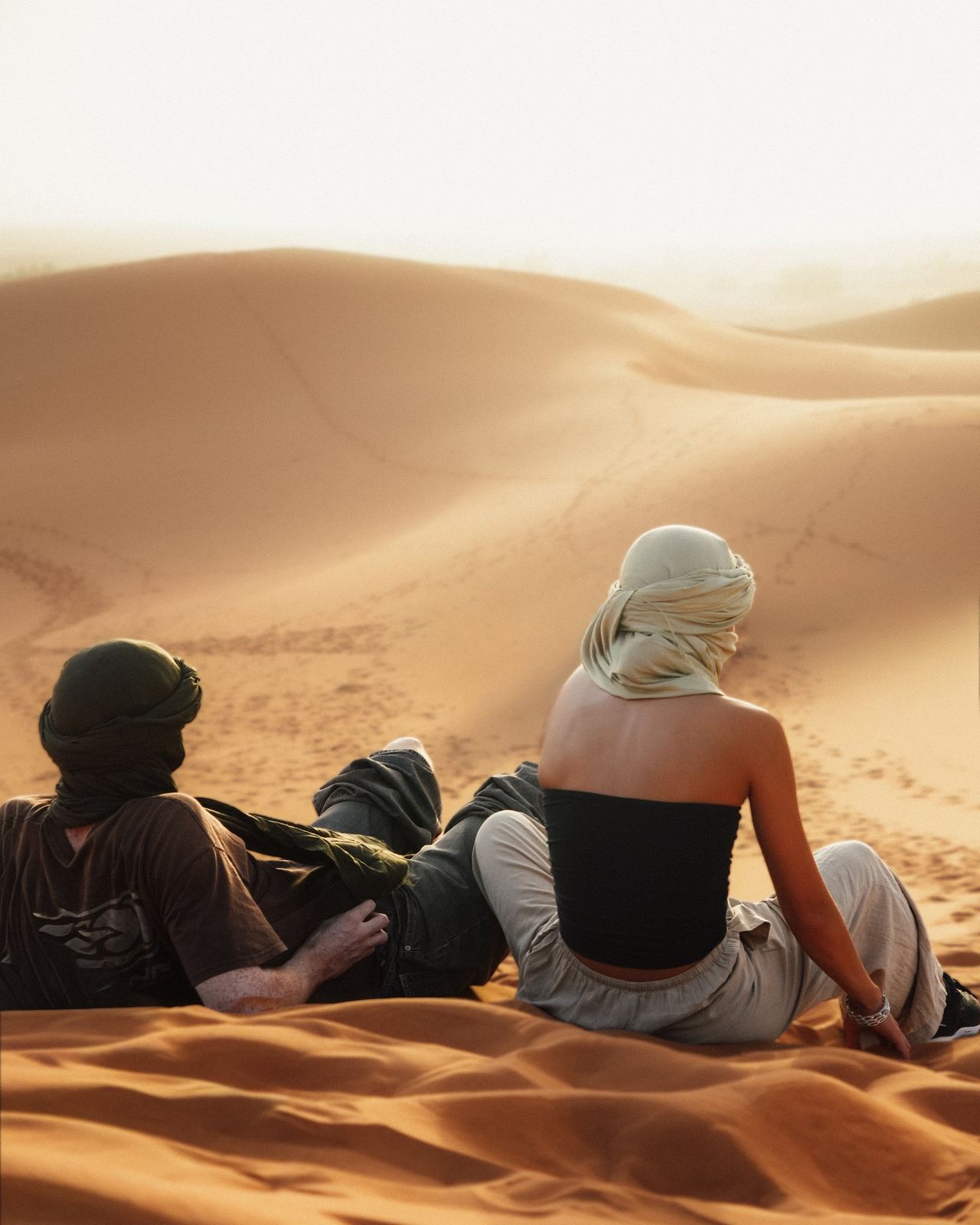 Due persone sedute sulla cresta di una duna nel deserto del Sahara