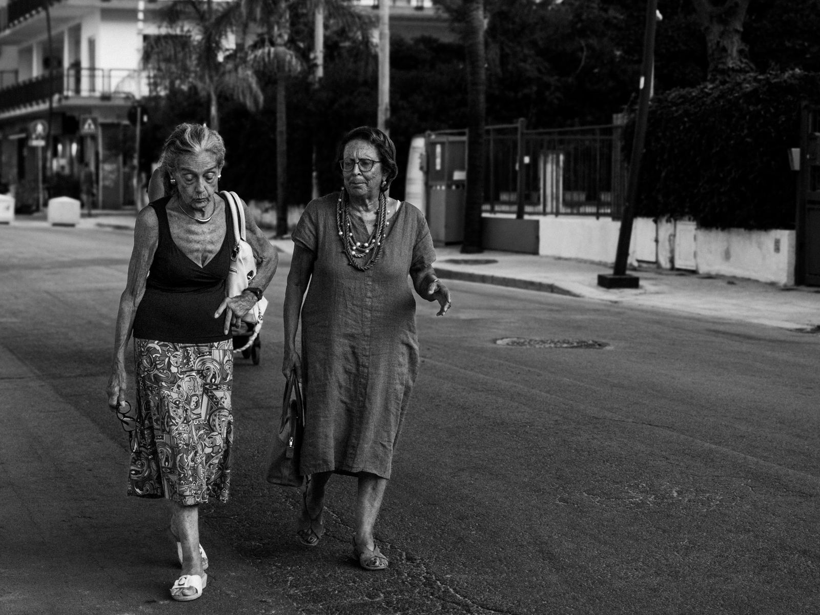 Due donne camminano lungo una strada assolata, bianco e nero
