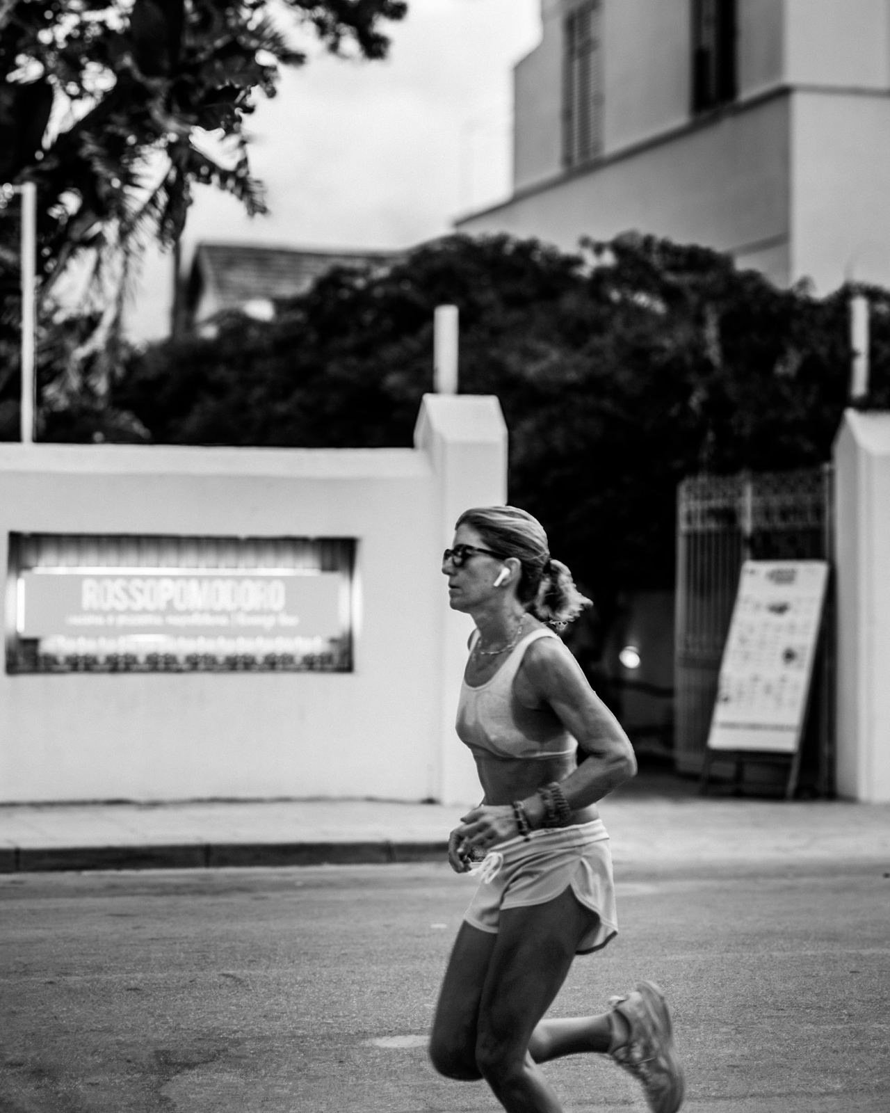 Ragazza che corre lungo un muro bianco, fotografia di strada in bianco e nero