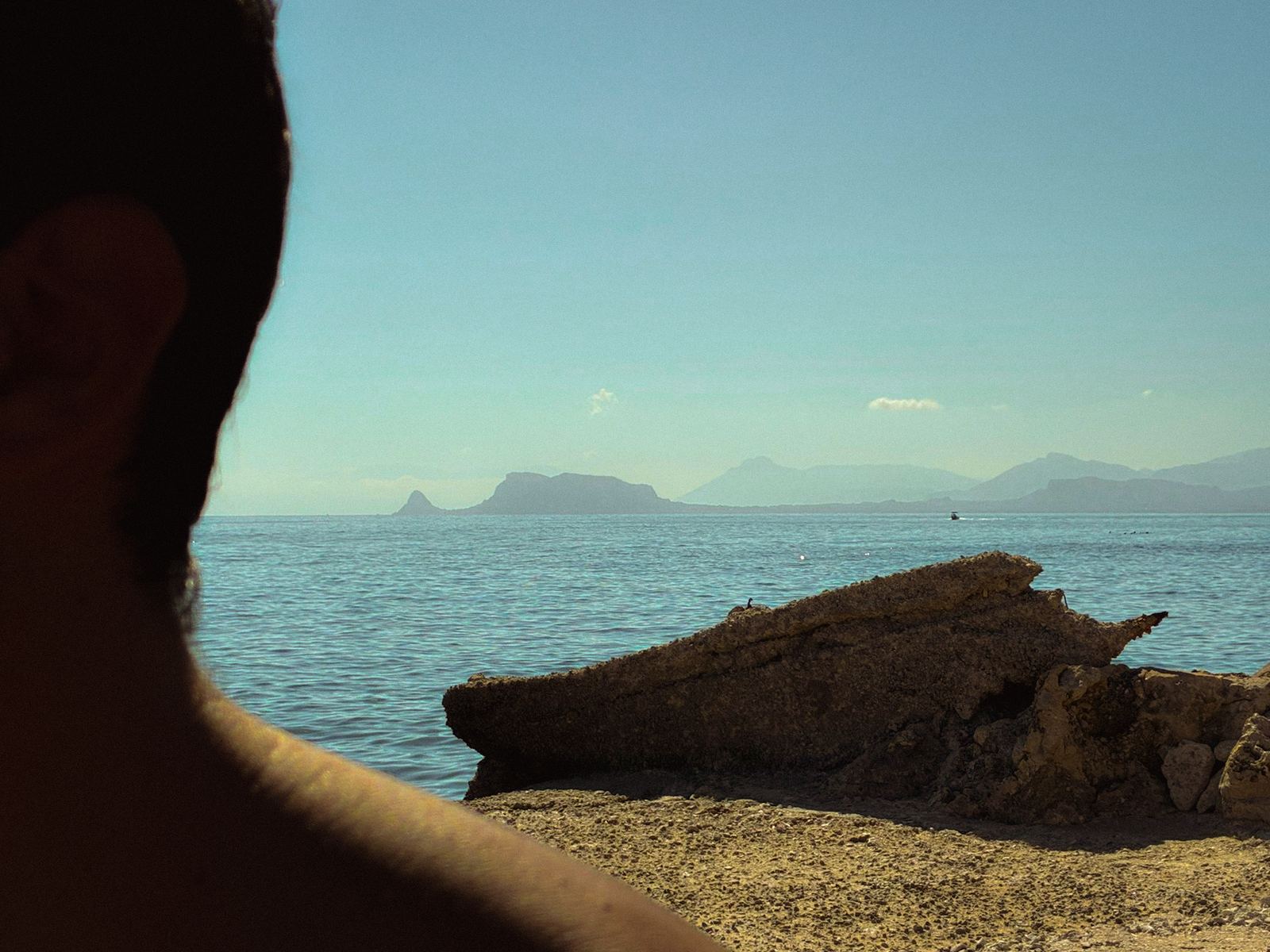 Costa siciliana con scogli e mare calmo, di fronte le isole all'orizzonte