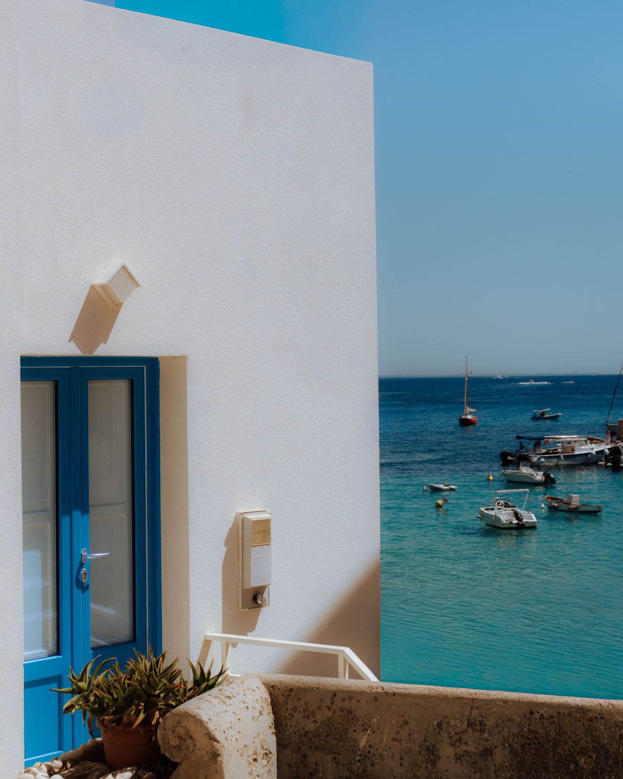 Casa bianca con porta blu affacciata sul mare, architettura mediterranea