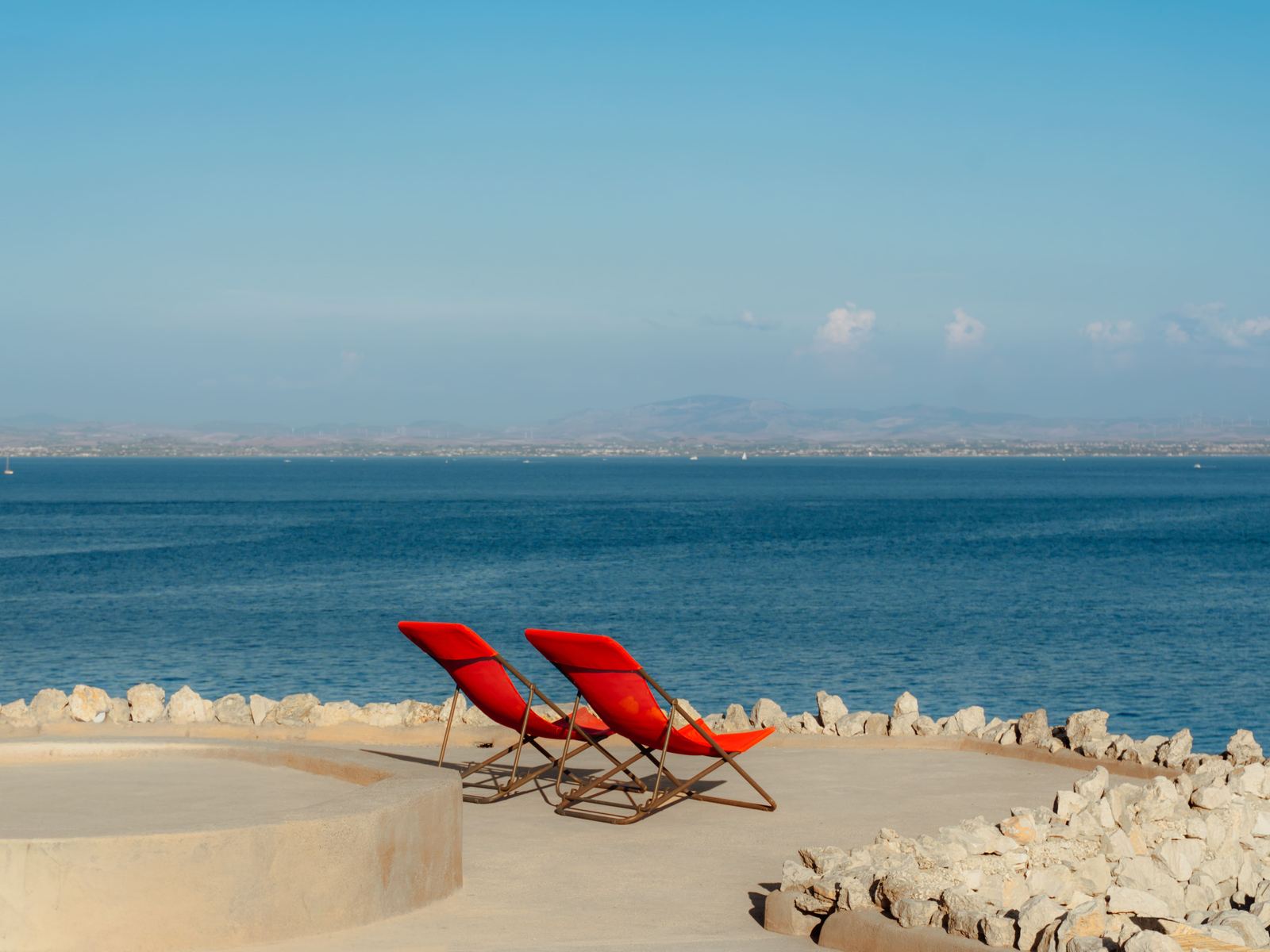 Due sdraio rosse su una terrazza sul mare