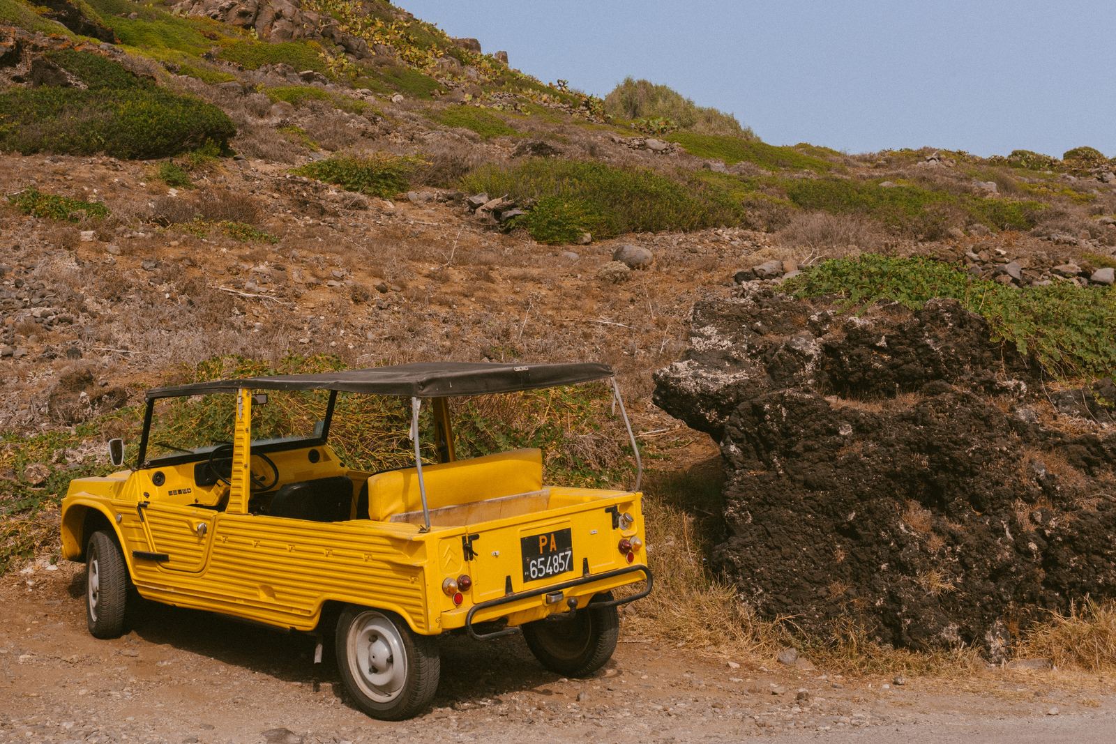 Mehari gialla parcheggiata su una strada sterrata fra la macchia mediterranea